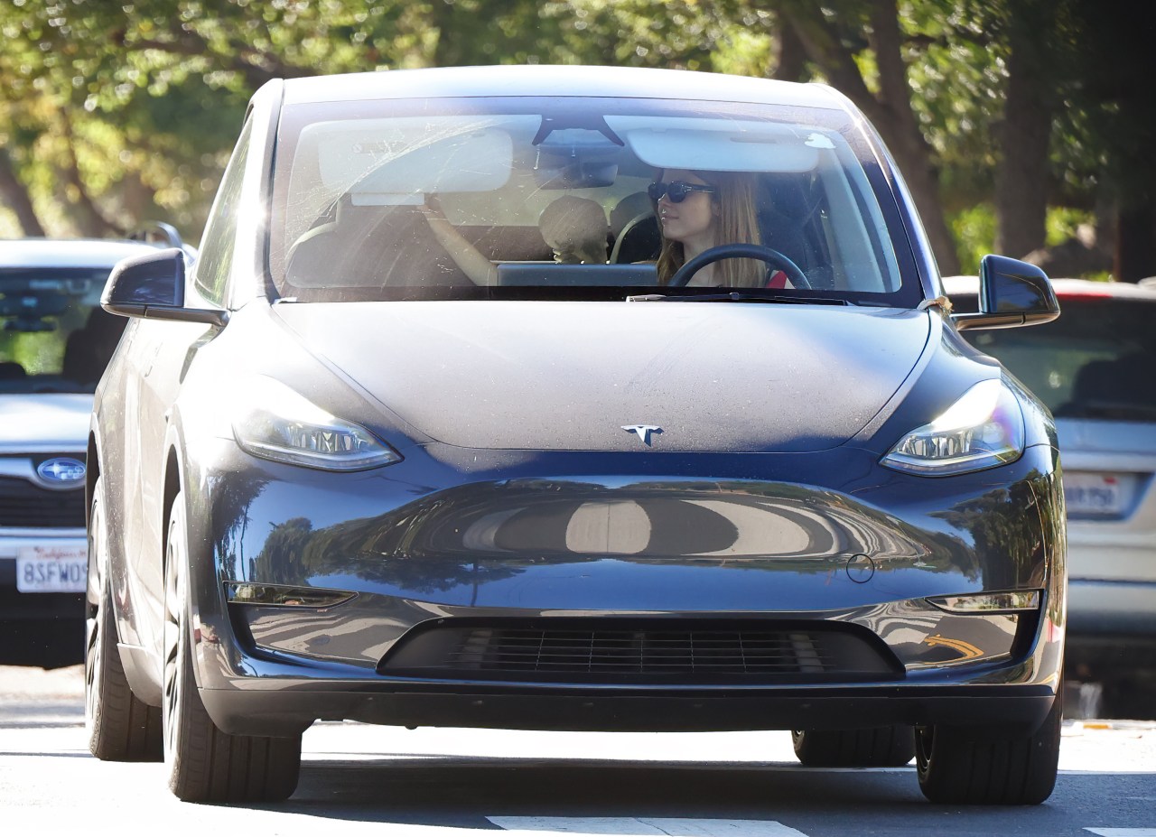Mia Goth sitting in a car with two skeleton decorations visible in the back seat